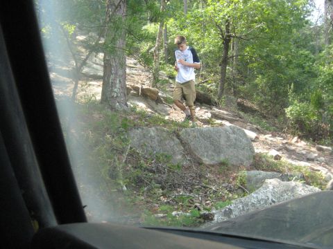 1978 Ford Bronco - View from inside a vehicle shows a person walking on a rocky, wooded trail.