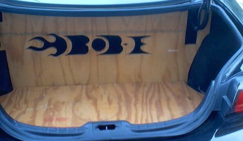 1999 Ford Taurus - The trunk of a car is open, revealing custom wood paneling with flame decals.