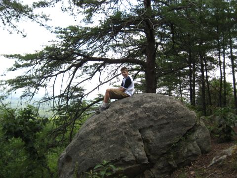 1978 Ford Bronco - Boy rests on a rock in a wooded area with a scenic view.