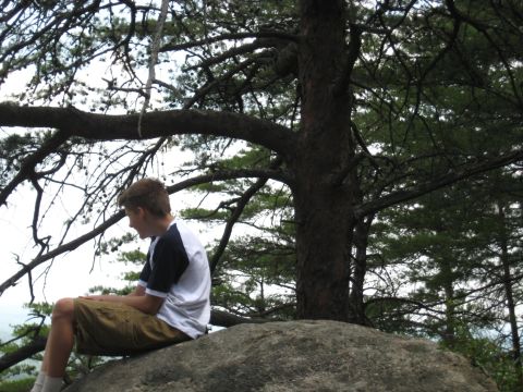 1978 Ford Bronco - A young person sits on a large rock, looking away from the camera, surrounded by trees.