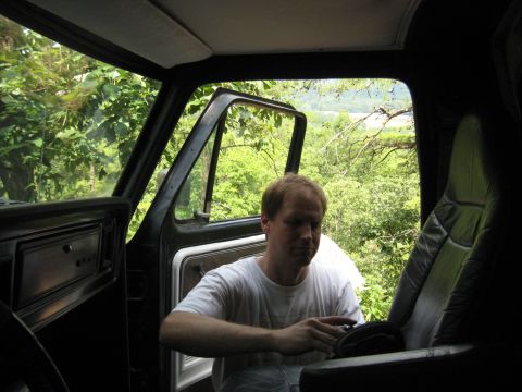 1978 Ford Bronco - Interior view of a 1978 Ford Bronco with a man seated inside, looking down at something in his hands.