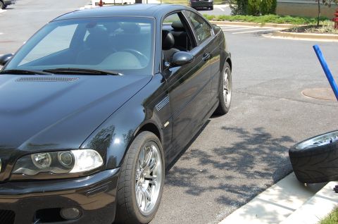 2002 BMW M3 - Black coupe with chrome wheels parked on asphalt, showing a side vent and front quarter view.
