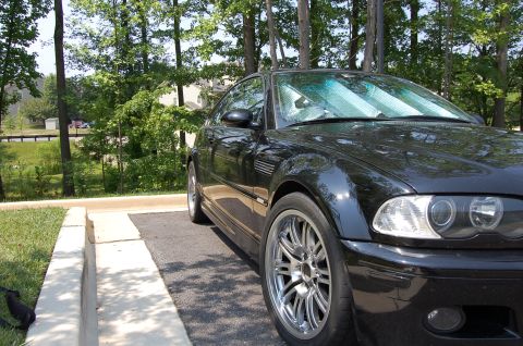 2002 BMW M3 - A black 2002 BMW M3 coupe is seen from a three-quarter front view, parked next to a curb.