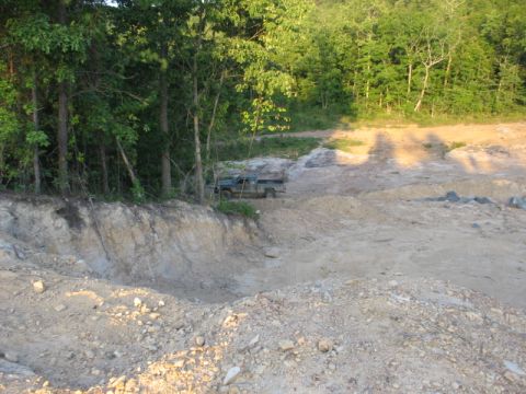 1978 Ford Bronco - A green pickup truck is parked on a dirt path next to a wooded area.