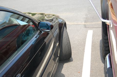 2002 BMW M3 - A black coupe is parked in a parking spot, very close to another vehicle.