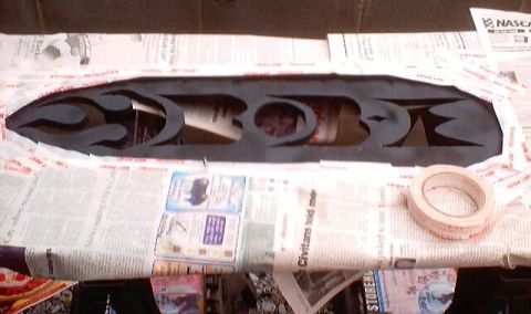 1999 Ford Taurus - A black cutout emblem with a tribal flame design is taped to newspaper, likely for a custom car project.