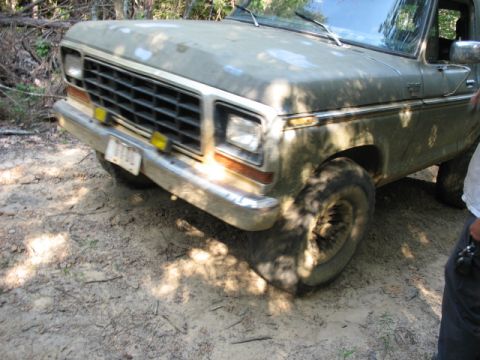 1978 Ford Bronco - A dusty 1978 Ford Bronco with off-road tires is seen from the front 3/4 angle on a dirt path.