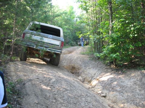 1978 Ford Bronco - Two SUVs navigate a challenging dirt trail through a wooded area.