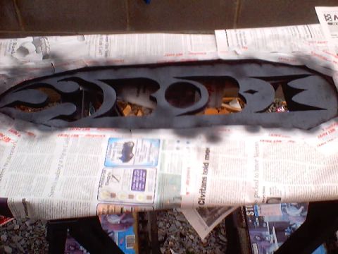 1999 Ford Taurus - A custom grille insert with flame cutouts is shown being painted, resting on newspaper.