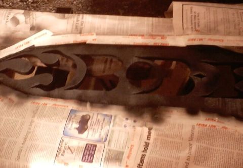 1999 Ford Taurus - Custom emblem with flame design, likely for a car trunk or grille, placed on newspaper.