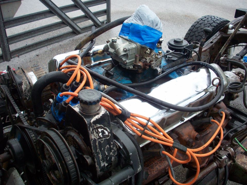 close-up of a vehicle engine with chrome valve covers and orange spark plug wires
