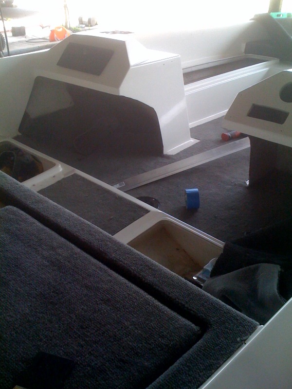 Interior of a boat with carpeted seats and white molded consoles