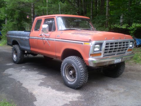 1979 Ford Bronco - This lifted Ford F-Series truck features a two-tone paint scheme with an orange cab and a dark-colored bed.