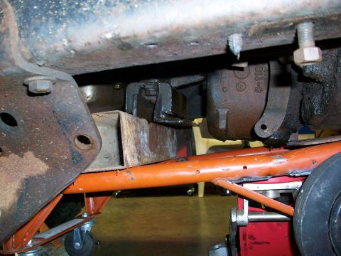 1979 Ford Bronco - Close-up of a vehicle's undercarriage, showing structural components and a jack supporting the frame. A part number is visible on a compone…