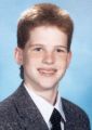 1977 Ford Mustang II - A portrait of a young person wearing a suit and tie, with a blue gradient background.