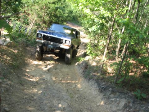 1978 Ford Bronco - A blue Ford Bronco navigates a steep, wooded trail.