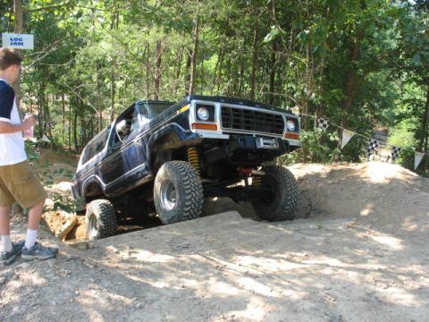 1978 Ford Bronco - A modified Ford Bronco navigates a challenging dirt obstacle on an off-road course.