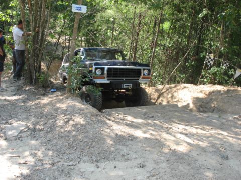 1978 Ford Bronco - This black 1978 Ford Bronco navigates a challenging off-road course, with a 'LOG JAM' sign visible in the background.