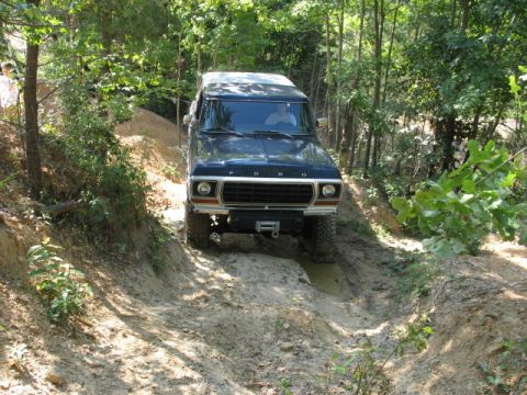 1978 Ford Bronco - 1978 Ford Bronco navigating a challenging dirt path in a wooded area.