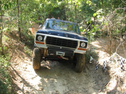 1978 Ford Bronco - A 1978 Ford Bronco navigates a challenging off-road course with checkered flags marking the path.