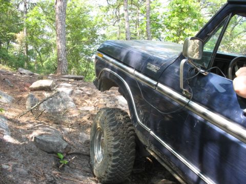 1978 Ford Bronco - A dark blue 1978 Ford Bronco navigates a challenging, rocky off-road path.