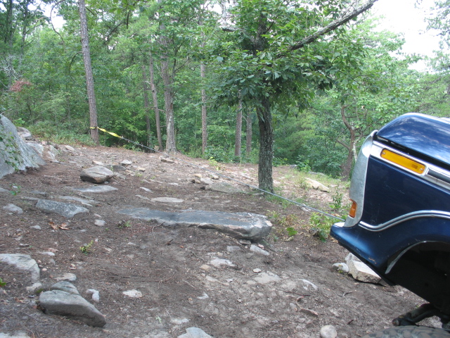 blue pickup truck on rocky, wooded trail