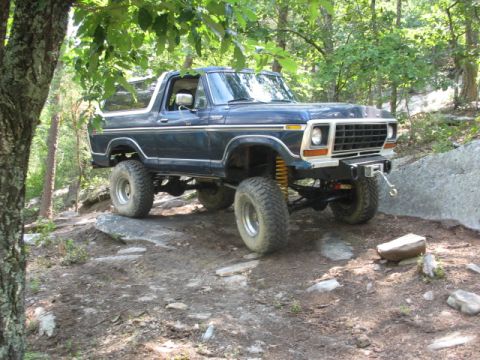 1978 Ford Bronco - This lifted 1978 Ford Bronco navigates a rocky, off-road path surrounded by trees.