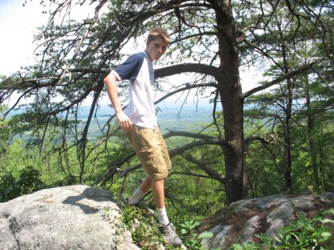 1978 Ford Bronco - A young man pauses on a rocky ledge overlooking a forested valley.