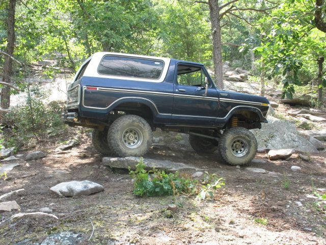 1978 Ford Bronco 3q-front view, blue with white top, off-roading on rocks