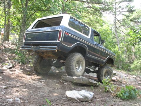 1978 Ford Bronco - 1978 Ford Bronco navigating a challenging off-road course in a wooded area.