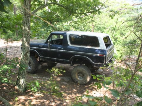 1978 Ford Bronco - This 1978 Ford Bronco is captured off-roading on a dirt path surrounded by trees.