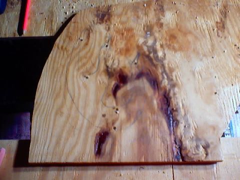 1999 Ford Taurus - A piece of plywood with circular markings and dark stains is shown on a workbench.