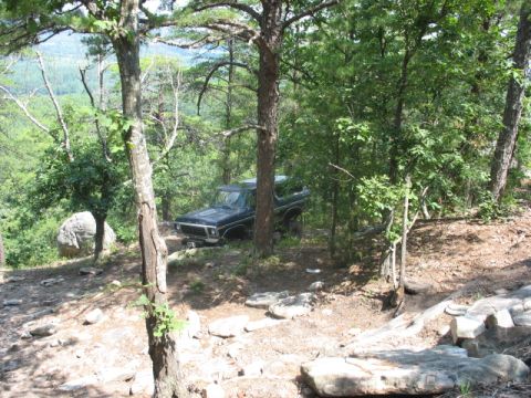 1978 Ford Bronco - 1978 Ford Bronco parked on a wooded trail, surrounded by trees and rocks.