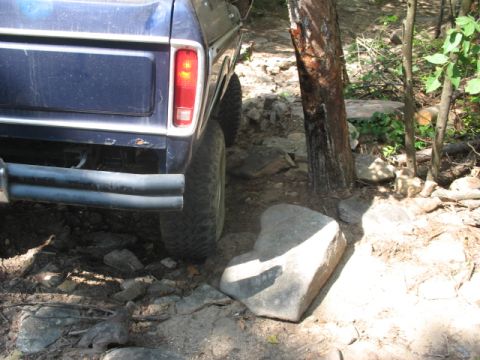 1978 Ford Bronco - 1978 Ford Bronco rear end maneuvering through a rocky, wooded off-road path.