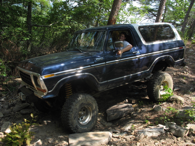 Blue 1978 Ford Bronco with white top on rocky terrain, driver visible