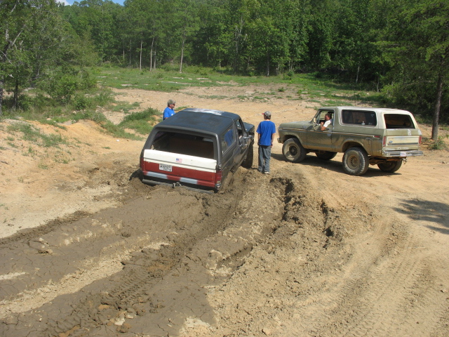 1978 Ford Bronco and another SUV stuck in mud with two people standing nearby