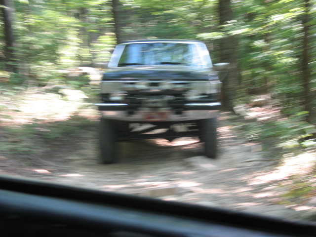 Dark SUV driving on a dirt road in a forest