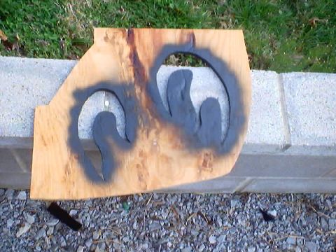 1999 Ford Taurus - A wooden board with a spray-painted stencil of the Dodge Ram logo sits on a concrete ledge.