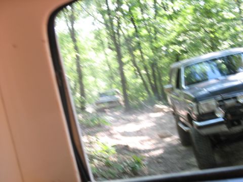 1978 Ford Bronco - Two trucks navigate a wooded trail, kicking up dust on the path ahead.