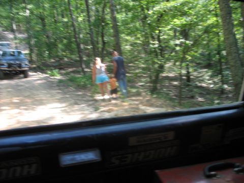 1978 Ford Bronco - View from inside a vehicle shows a dirt path in a wooded area with people and another vehicle.