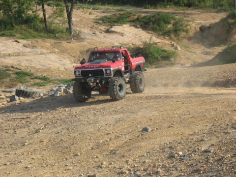 1978 Ford Bronco - Modified 1978 Ford Bronco tackling an off-road trail with large tires and suspension lift.