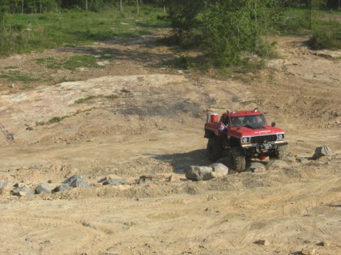 1978 Ford Bronco - A modified red pickup truck navigates a rocky off-road course.