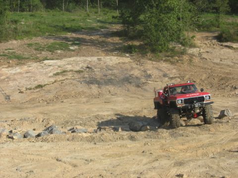 1978 Ford Bronco - A red 1978 Ford Bronco navigates a rocky, off-road terrain with a winch and lifted suspension.