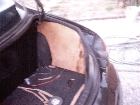 1999 Ford Taurus - The interior of a car's trunk is shown with exposed wiring and a tan insulation panel. The trunk lid is open.