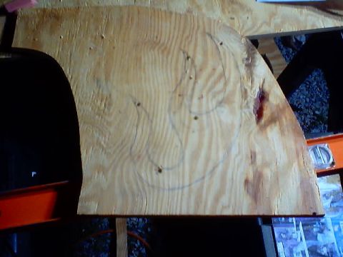 1999 Ford Taurus - A piece of plywood with a drawn outline and some holes is shown, with a black curved edge visible on the left.