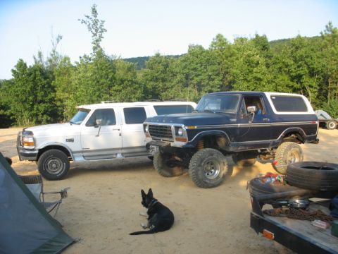 1978 Ford Bronco - A lifted 1978 Ford Bronco and a white SUV are parked on a dirt lot with trees in the background.