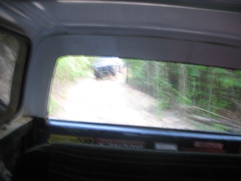 1978 Ford Bronco - Looking out the back of a vehicle at another off-road vehicle navigating a wooded dirt road.