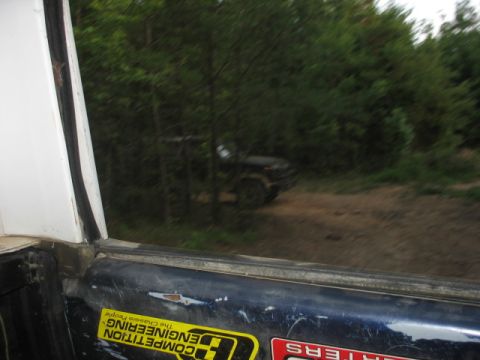 1978 Ford Bronco - A vehicle is seen driving on a dirt path surrounded by dense trees.