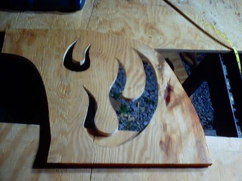 1999 Ford Taurus - A wooden cutout shaped like a flame is shown, with gravel and dark structures visible through its openings.