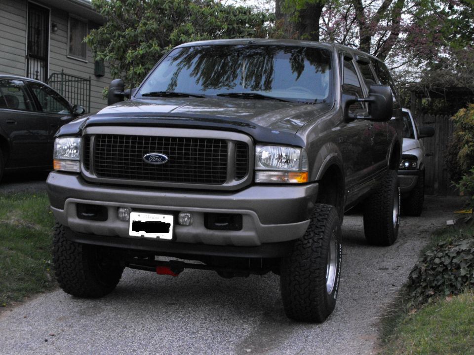 Lifted gray Ford Excursion SUV on BFGoodrich tires parked in a gravel driveway.